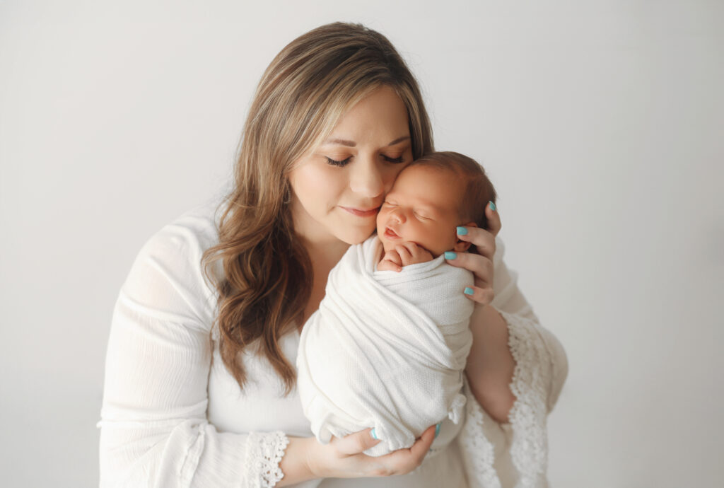 a picture of a mom holding baby boy in Claremore newborn photography studio 